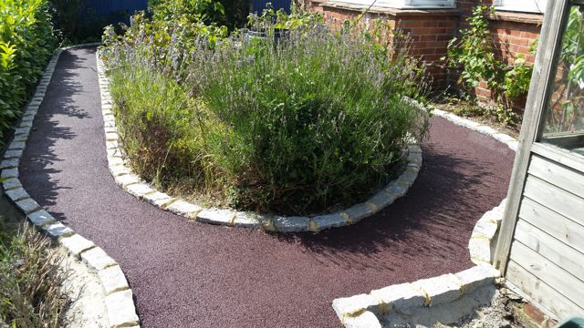 Red-coloured tarmac surfaced garden path with granite sett block edging