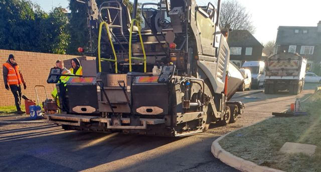 Asphalt paver laying material beside a kerb