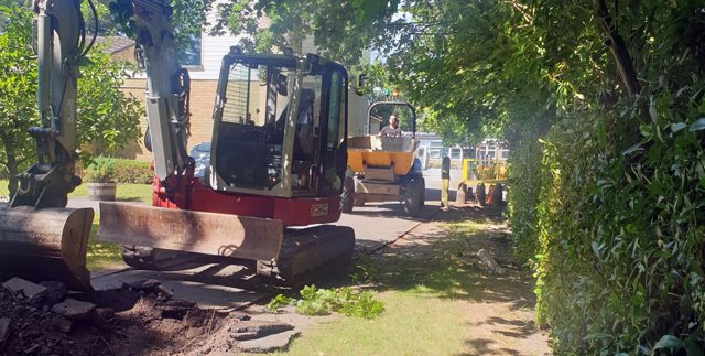 Excavator removing damaged surfacing along an access road