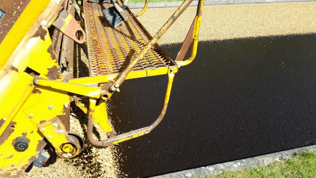 Chip spreader applying aggregate over bitumen binder